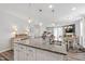 Open-concept kitchen features a granite island with pendant lighting and stainless steel sink, blending into dining and living spaces at 321 Everly Mist Way, Wake Forest, NC 27587