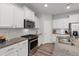 Well-lit kitchen featuring white cabinets, granite countertops, and modern stainless steel appliances at 321 Everly Mist Way, Wake Forest, NC 27587