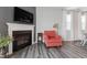 Living room showcasing a fireplace with a mounted TV above, complemented by a stylish accent chair and hardwood flooring at 321 Everly Mist Way, Wake Forest, NC 27587