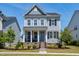 Charming two-story home featuring a welcoming porch with a blue front door and beautiful landscaping at 3224 Wishing Well Wynd, Apex, NC 27502