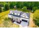 Aerial view of a white house with a covered porch, black roof, and a two car garage at 3281 Phillips Chapel Rd, Haw River, NC 27258
