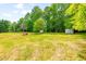 Expansive backyard featuring mature trees and a storage shed, perfect for outdoor activities at 3281 Phillips Chapel Rd, Haw River, NC 27258