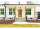 Inviting front porch with wood columns and stone base, leading to a charming wood front door at 3281 Phillips Chapel Rd, Haw River, NC 27258