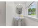 Bright bathroom featuring a pedestal sink, oval mirror, and window at 3425 Brentwood Rd, Raleigh, NC 27604