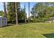 Backyard view featuring mature trees, a storage shed and a well maintained lawn at 3501 Arrowwood Dr, Raleigh, NC 27604