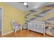 Bright Bedroom featuring a white crib, hardwood floors, geometric wall design, a window, and stylish decor at 3501 Arrowwood Dr, Raleigh, NC 27604