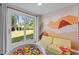 Playroom with ball pit, sliding glass doors to a large yard, a comfy yellow couch and colorful mountain mural at 3501 Arrowwood Dr, Raleigh, NC 27604