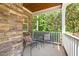 Relaxing covered front porch with cozy seating, stone accent wall, and serene wooded view at 3612 Carriage Dr, Raleigh, NC 27612