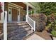Inviting front porch with stone steps, wood ceiling, stone accent wall, white railing, and landscaped surroundings at 3612 Carriage Dr, Raleigh, NC 27612