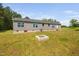 View of the backyard showing the exterior, with vinyl siding, windows, and a small fire pit feature at 380 Perdues Rd, Louisburg, NC 27549