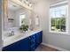 Bathroom with navy blue double vanity, white counters, decorative mirror, and natural light at 401 Onondaga Ct, Holly Springs, NC 27540