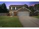 Home exterior at dusk features a teal front door, a garage and well-kept lawn at 401 Onondaga Ct, Holly Springs, NC 27540