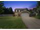Charming two-story home with a well-manicured lawn, two car garage, and a basketball hoop in the driveway at twilight at 401 Onondaga Ct, Holly Springs, NC 27540
