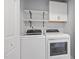 Modern laundry room features white cabinets, shelving, and new front-loading machines at 401 Onondaga Ct, Holly Springs, NC 27540