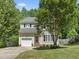 Traditional two-story home with an attached garage, a well-maintained lawn, and lush landscaping at 408 Blooming Meadows Rd, Holly Springs, NC 27540