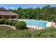Community pool surrounded by lounge chairs, umbrellas, green foliage, and a clubhouse at 4535 Sugarbend Way, Raleigh, NC 27606