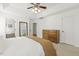 Bright bedroom featuring a tray ceiling, ceiling fan, dresser, and a view into the connected bathroom at 5213 Holly Ridge Farm Rd, Raleigh, NC 27616