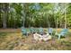 Backyard featuring a beautiful fire pit circled by six Adirondack chairs surrounded by mature trees at 5402 Shealtiel Way, Rougemont, NC 27572