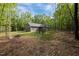 Wide view of the house and backyard featuring a back deck and outdoor furniture in a wooded lot at 5402 Shealtiel Way, Rougemont, NC 27572