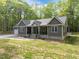 Charming exterior of a gray home featuring a covered porch, white trim, and a well-maintained front yard at 5402 Shealtiel Way, Rougemont, NC 27572
