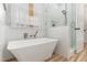 Bright bathroom featuring a modern tub, tiled walls, and a glass-enclosed shower at 5504 Creekdale Cir, Raleigh, NC 27612