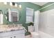 Green-walled bathroom featuring a granite countertop, toilet, and shower-tub combo at 5504 Creekdale Cir, Raleigh, NC 27612