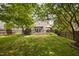 A large backyard featuring green grass, a wooden fence, a patio and wood deck, and ample shade trees at 5512 Bridgeman Ct, Durham, NC 27703