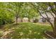 A large backyard featuring green grass, a wooden fence, a patio and wood deck, and ample shade trees at 5512 Bridgeman Ct, Durham, NC 27703