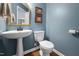 Powder room features blue walls, a pedestal sink, mirror, and wood-look floors at 5512 Bridgeman Ct, Durham, NC 27703
