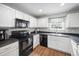Kitchen boasts white cabinets, black appliances and countertops, and wood-look flooring at 5512 Bridgeman Ct, Durham, NC 27703