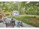 Spacious backyard with patio, shed, lush trees, and a wooden fence at 5642 Falkirk Dr, Durham, NC 27712