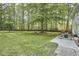 Expansive backyard with patio seating, a grill, and lush green trees at 5642 Falkirk Dr, Durham, NC 27712