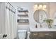 Stylish bathroom features a modern vanity, round mirror, decorative floating shelves, and a shower with a striped curtain at 5642 Falkirk Dr, Durham, NC 27712