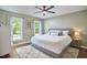 Bright bedroom featuring a comfortable king bed, ceiling fan, and natural light from two large windows at 5642 Falkirk Dr, Durham, NC 27712