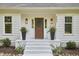 Inviting front porch with a wreath, black planters, and freshly painted white brick steps at 5642 Falkirk Dr, Durham, NC 27712