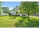 Well-manicured lawn and mature trees accent this charming single-story home with neutral siding and dark shutters at 6324 Daybreak Dr, Wake Forest, NC 27587