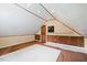 Sloped attic area featuring wood-paneled walls, a small window, and a newly installed carpet at 6509 Mountain Brook Ln, Raleigh, NC 27615