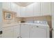 Efficient laundry room featuring white cabinets, sink and counter space, with a modern washer and dryer at 6509 Mountain Brook Ln, Raleigh, NC 27615