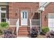 Charming front entrance with brick steps, decorative shrubs, and stylish sconces on either side of the door at 7 Bonham Ct, Durham, NC 27703