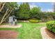 Picturesque backyard with a stone wall, mature trees, lush green lawn, and playset at 712 Evanvale Ct, Cary, NC 27518