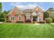 Stately brick home with manicured lawn, mature trees, and charming architectural details at 712 Evanvale Ct, Cary, NC 27518