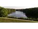 Scenic lake view with wooded shoreline, grassy fields, and a path at 7401 Ray Rd, Raleigh, NC 27613