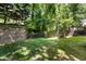A backyard with a brick wall, some trees, and a glimpse of a deck at 7508 Venture Ct, Raleigh, NC 27615