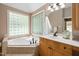 Bathroom featuring a soaking tub with jets and a vanity with wood cabinets at 7508 Venture Ct, Raleigh, NC 27615