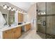 Bright bathroom with double vanity sinks, wood cabinetry, and a glass-enclosed shower at 7508 Venture Ct, Raleigh, NC 27615