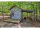 Garden shed nestled among mature trees, featuring a charming deck and adjacent wooded area at 800 Oxbow Crossing Rd, Chapel Hill, NC 27516