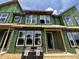 Modern townhome's exterior showcases large windows, green sheathing, and a brick pavers, offering a glimpse of contemporary living at 805 Fireship Rd, Fuquay Varina, NC 27526