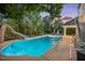 Spacious backyard with a slide leading into a sparkling pool, surrounded by lush greenery and mature trees at 817 Highwater Pl, Fuquay Varina, NC 27526