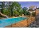 Inviting backyard pool with a slide, basketball hoop, deck, stairs, and mature trees for added privacy at 817 Highwater Pl, Fuquay Varina, NC 27526