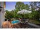 Relaxing deck with a table and chairs, shaded by an umbrella, overlooking the lush backyard and pool area at 817 Highwater Pl, Fuquay Varina, NC 27526